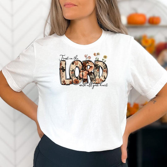A woman wearing a white t-shirt with a floral design and text printed on it.