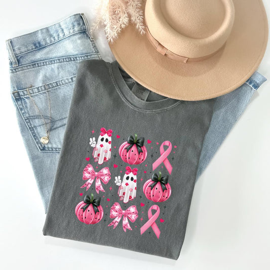a casual outfit consisting of a gray t-shirt with a graphic design featuring pink pumpkins, ghostly figures, and pink ribbons, along with a beige hat.