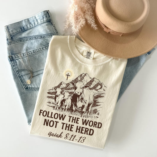 a white t-shirt with a graphic design, a pair of jeans, and a beige hat, all laid out on a white surface.
