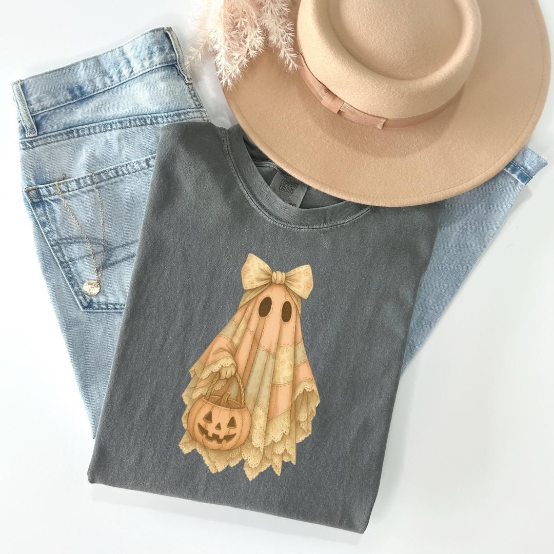 a casual outfit consisting of a gray t-shirt with a Halloween-themed design, a pair of blue jeans, and a beige hat.