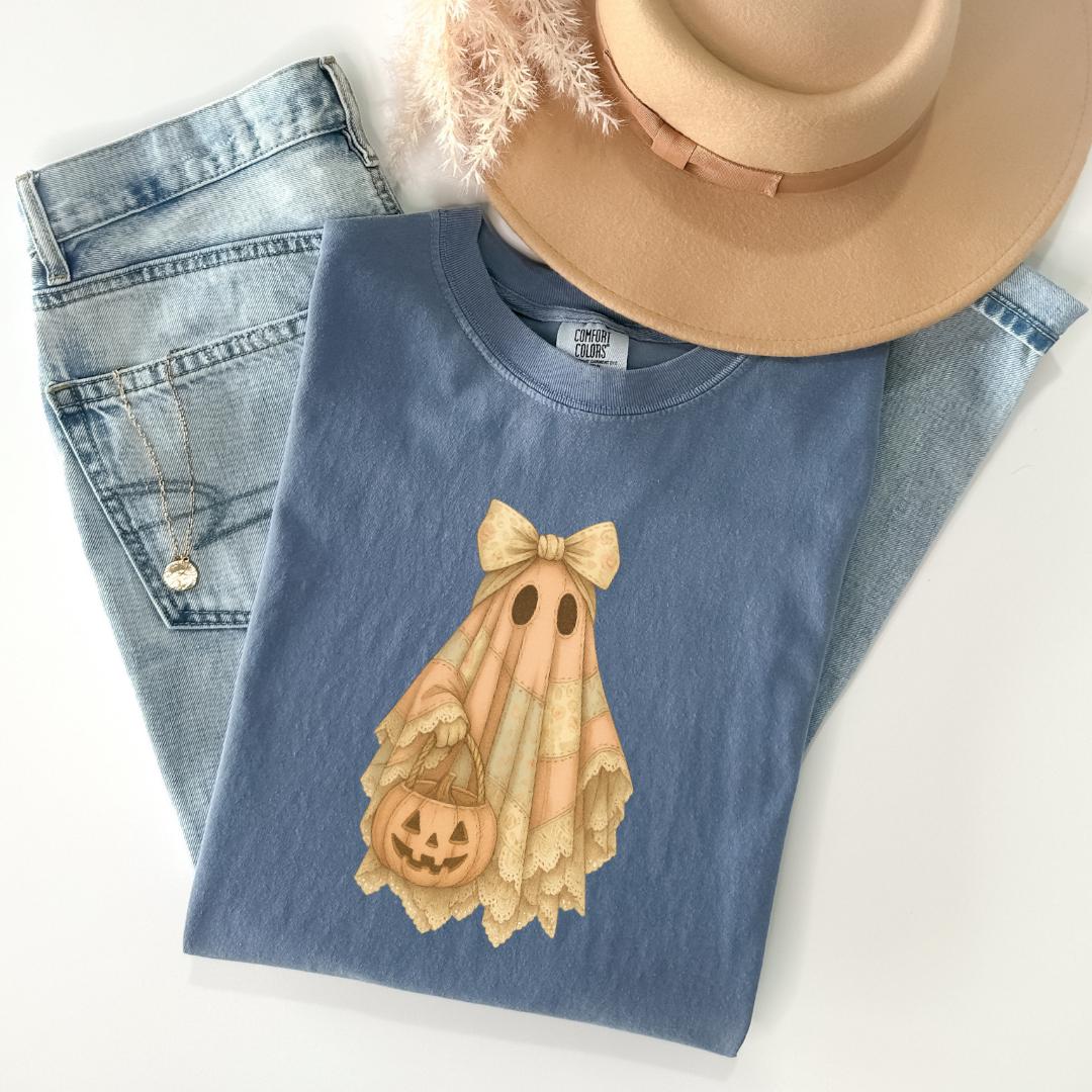 a casual outfit consisting of a blue t-shirt with a ghost design, a pair of blue jeans, and a beige hat.