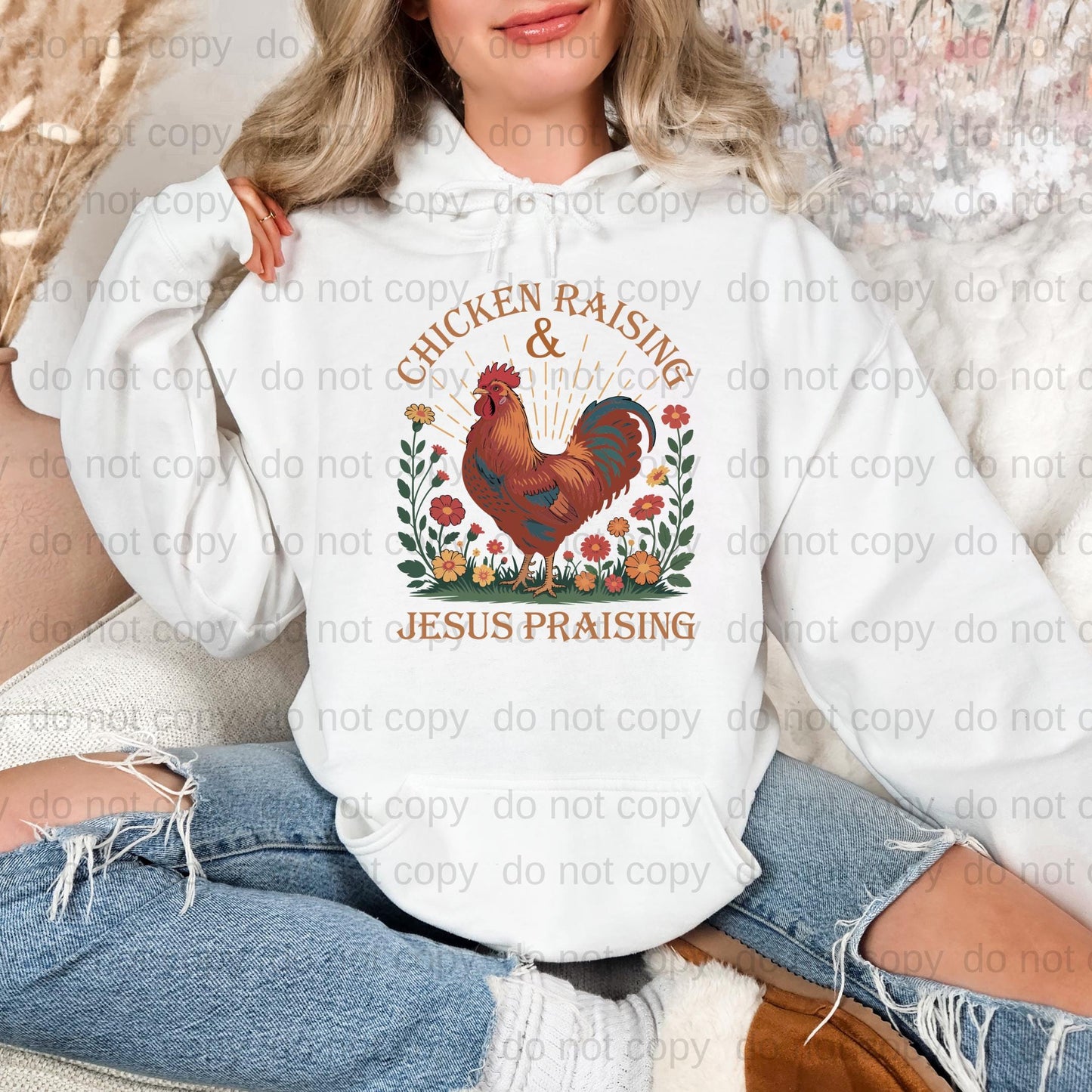 A woman wearing a white hoodie with a graphic design of a rooster and flowers, along with the text "Chicken Raising & Jesus Praising".