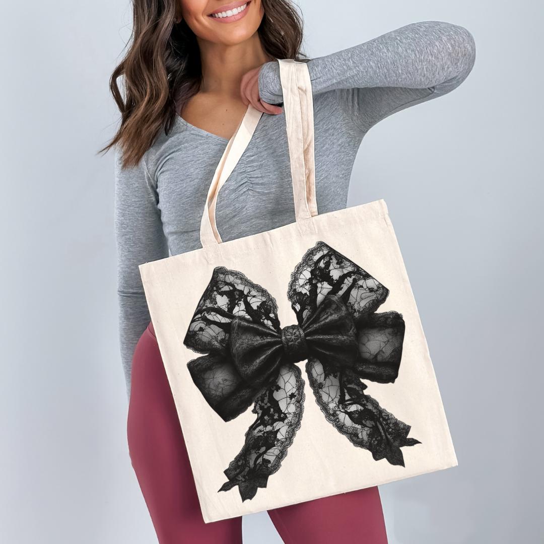 A woman is holding a large tote bag with a black lace bow design on it.