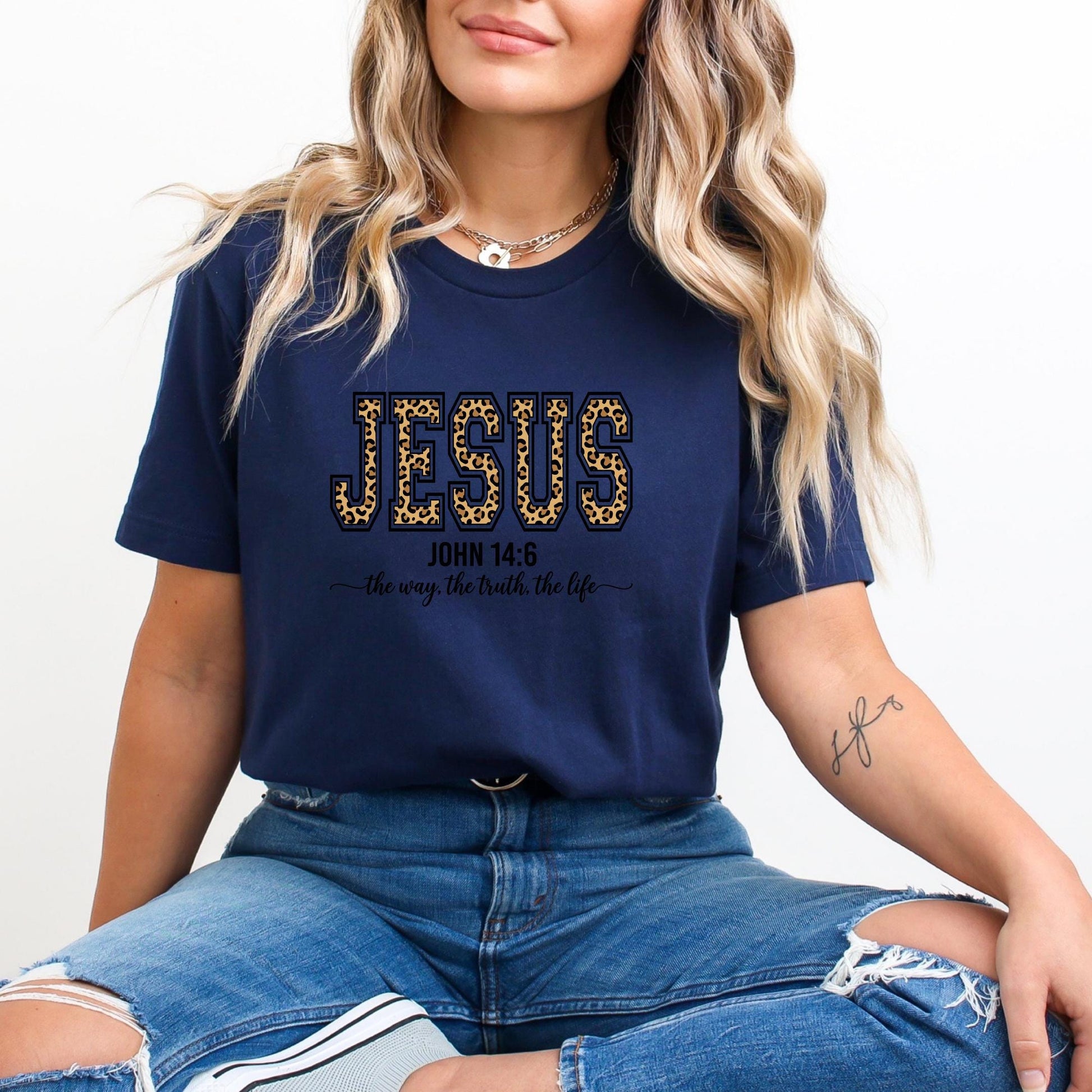 A woman wearing a navy blue t-shirt with the text "JESUS" and "the way the truth the life" printed on it, along with a Bible verse reference.