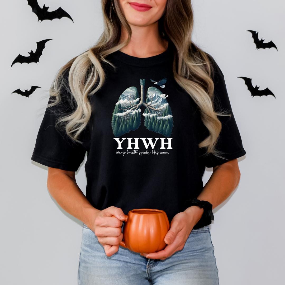 A woman with long blonde hair is holding a pumpkin and a mug, with a t-shirt featuring a graphic of lungs and bats printed on it.
