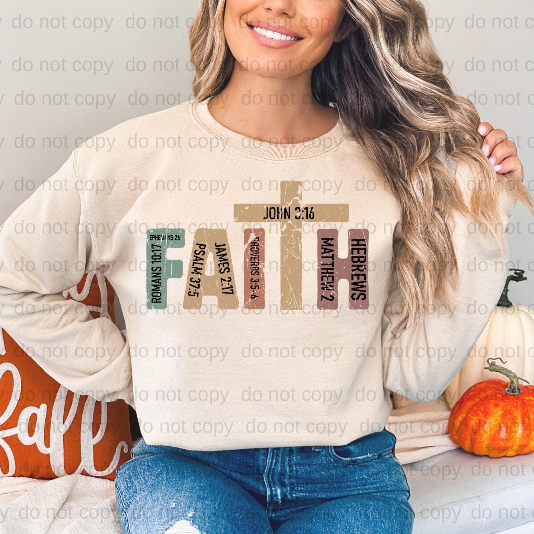 A woman wearing a white sweatshirt with a graphic design of the cross and the text "Faith" printed on it.