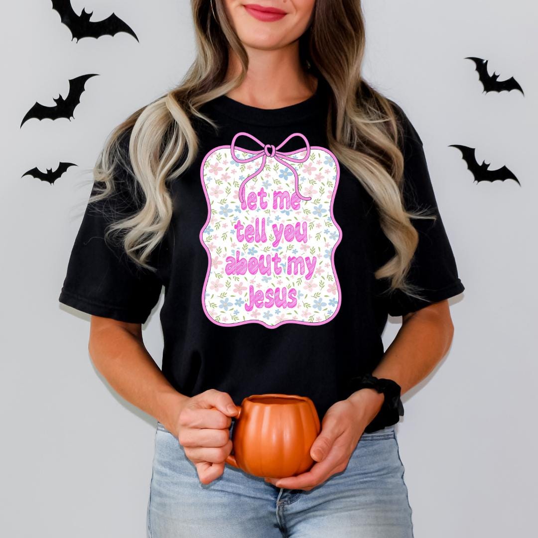 A woman wearing a black t-shirt with a graphic design and holding a pumpkin-shaped mug.