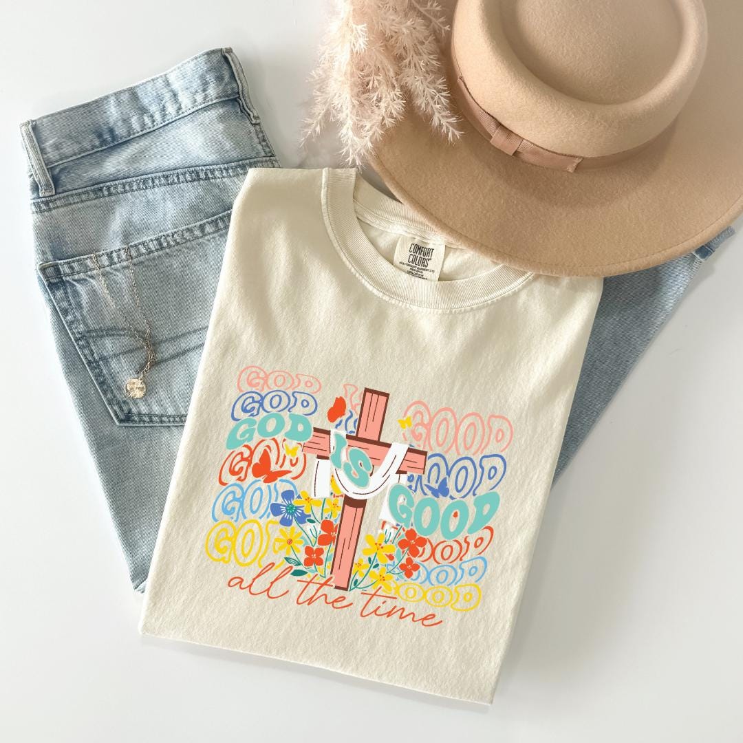 A casual outfit consisting of a white t-shirt with a colorful graphic design, a pair of blue jeans, and a beige hat.