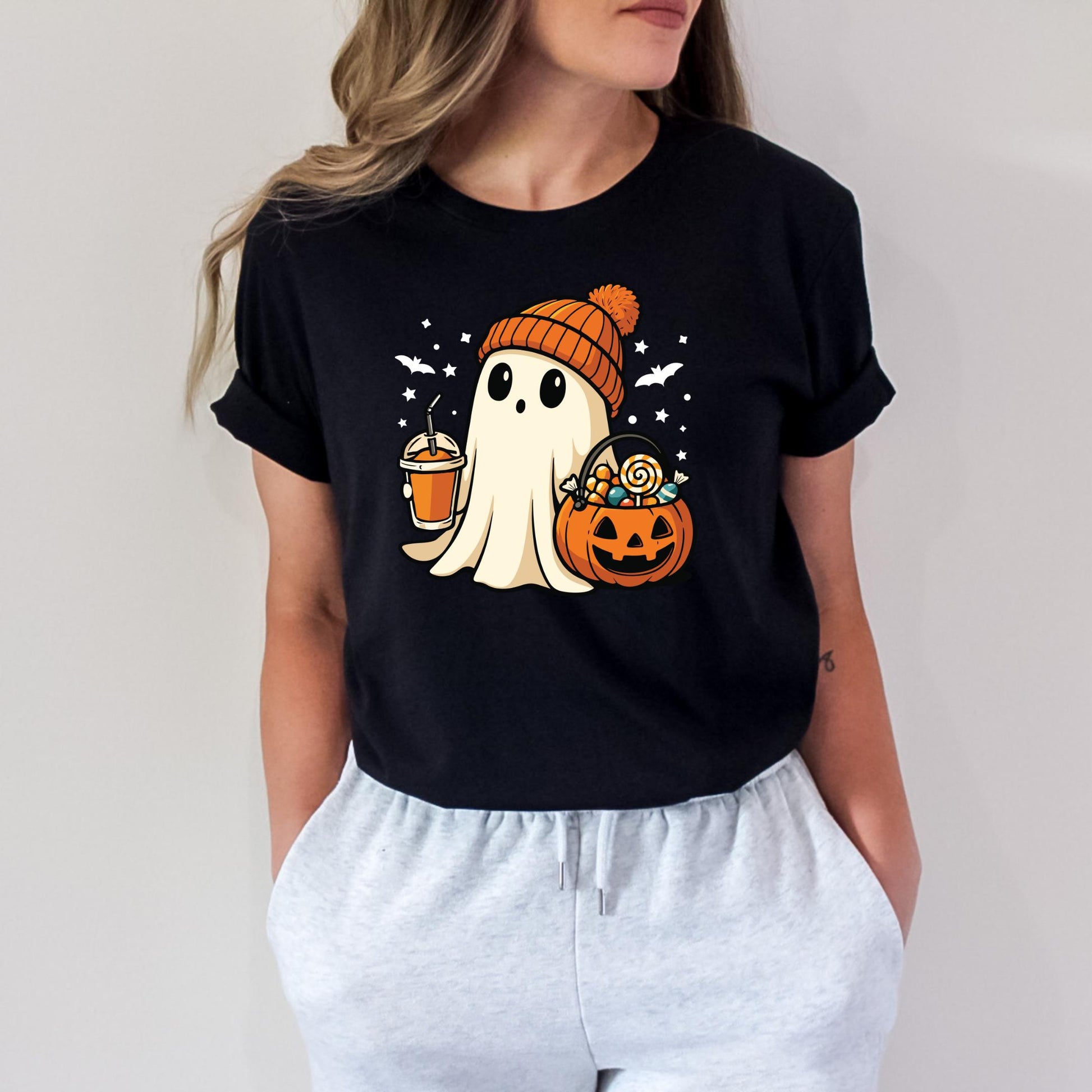 A woman wearing a black t-shirt with a graphic of a ghost holding a pumpkin and a cup of coffee.