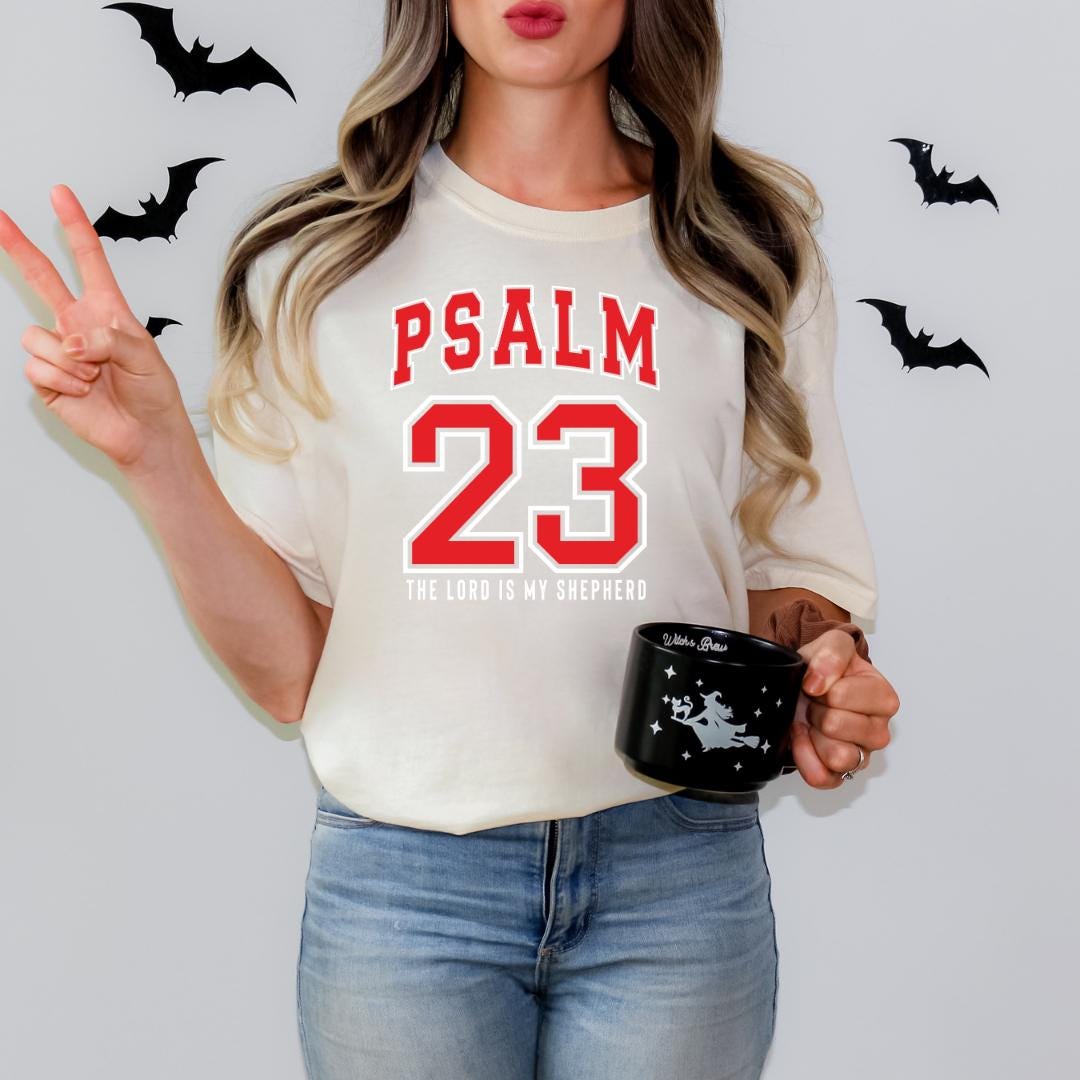 A woman wearing a white t-shirt with the text "PSALM 23" and holding a black mug with a star design.