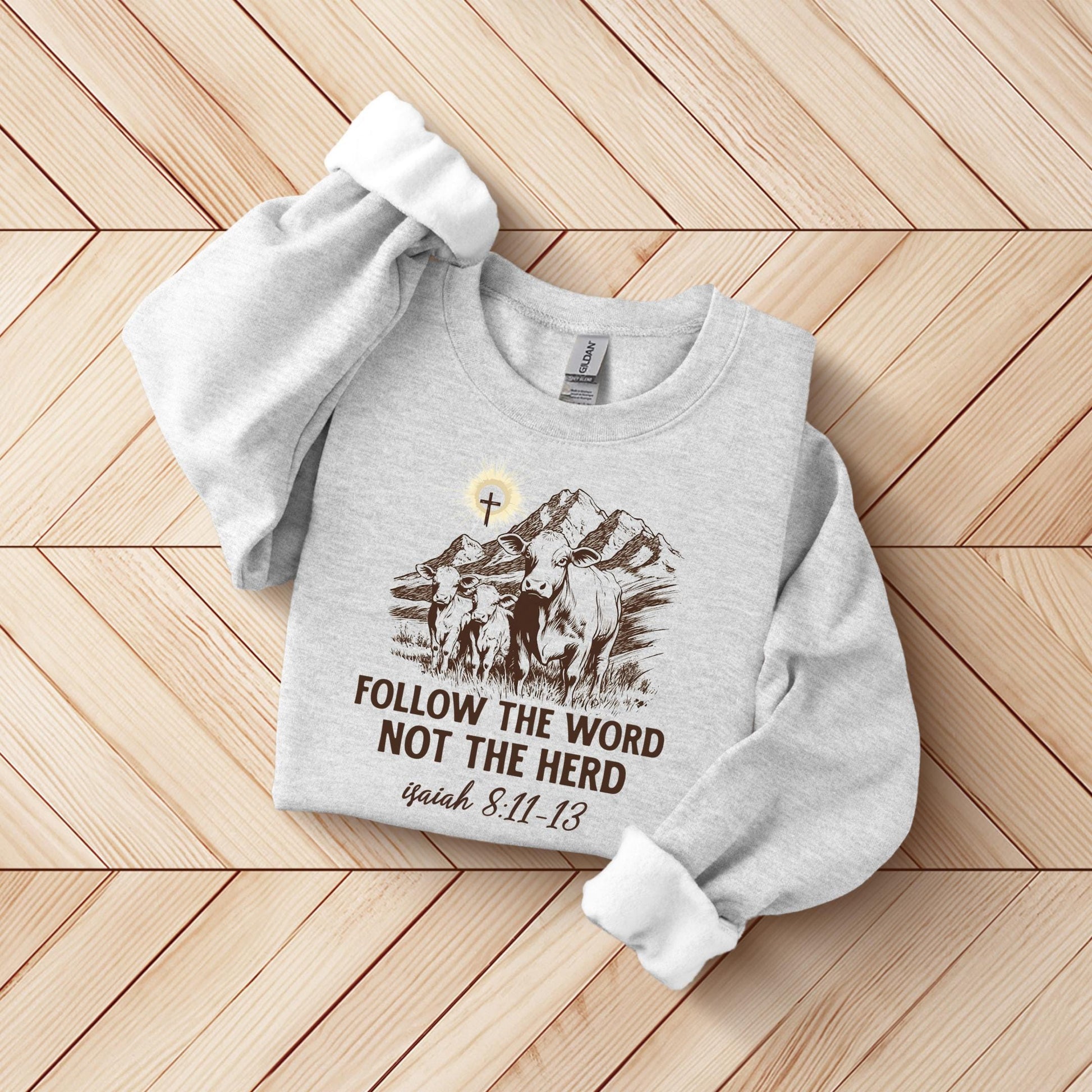 A gray sweatshirt with a graphic design and text printed on it, laid out on a wooden surface.