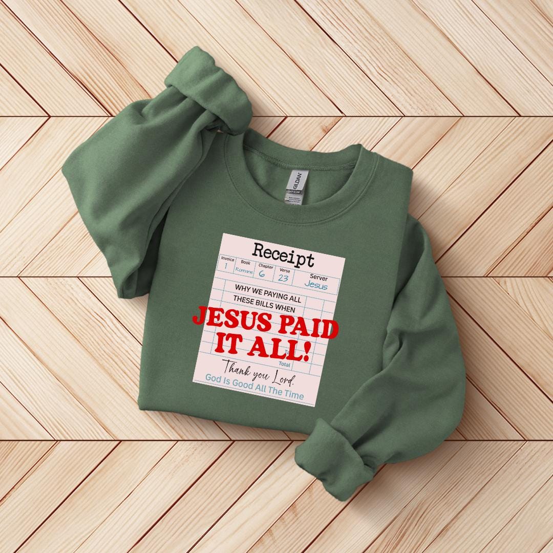 A green sweatshirt with a white receipt-style label printed on it, placed on a wooden surface.