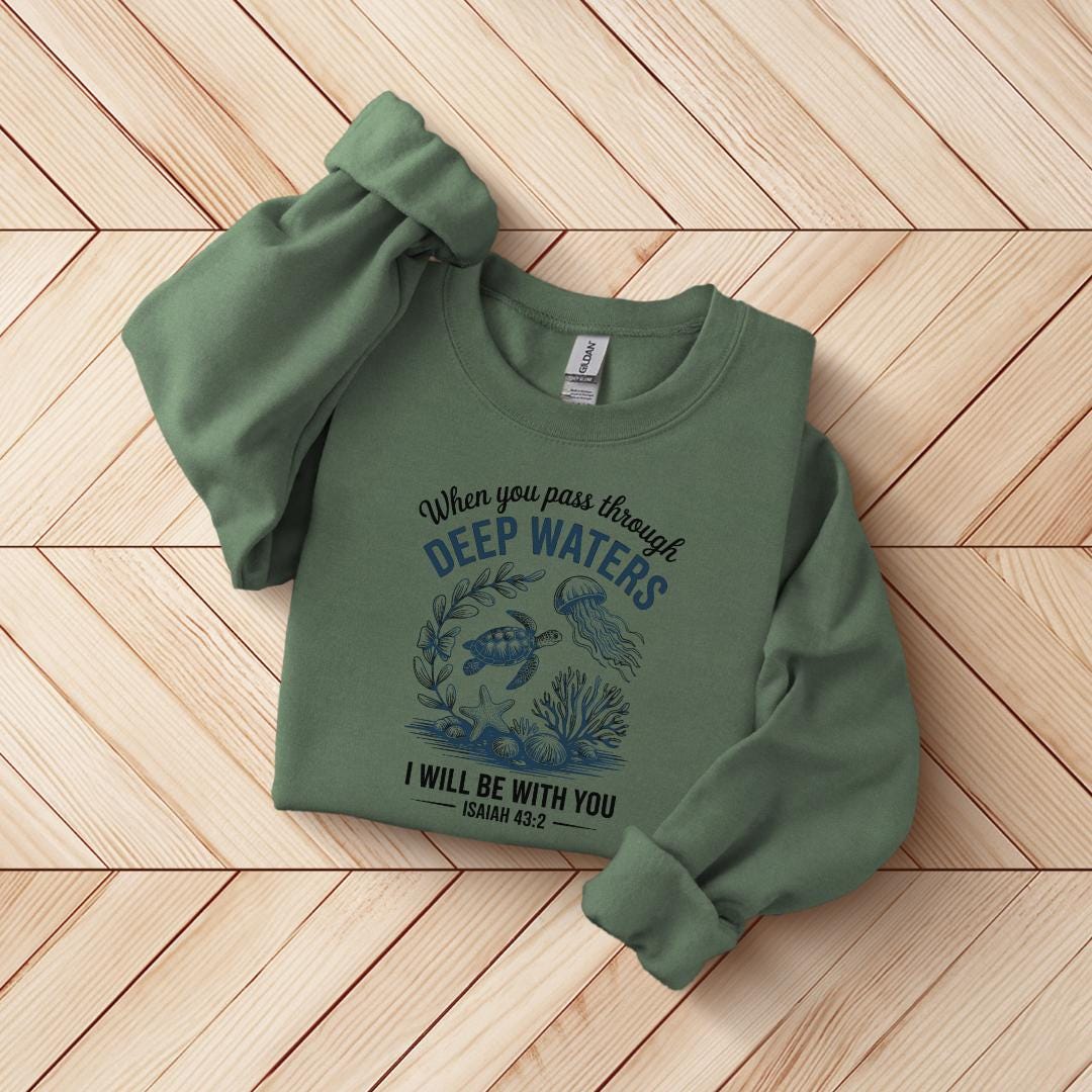 A green sweatshirt with a printed design on it, featuring a marine scene and text that reads "When you pass through DEEP WATERS I WILL BE WITH YOU Isaiah 43:22".