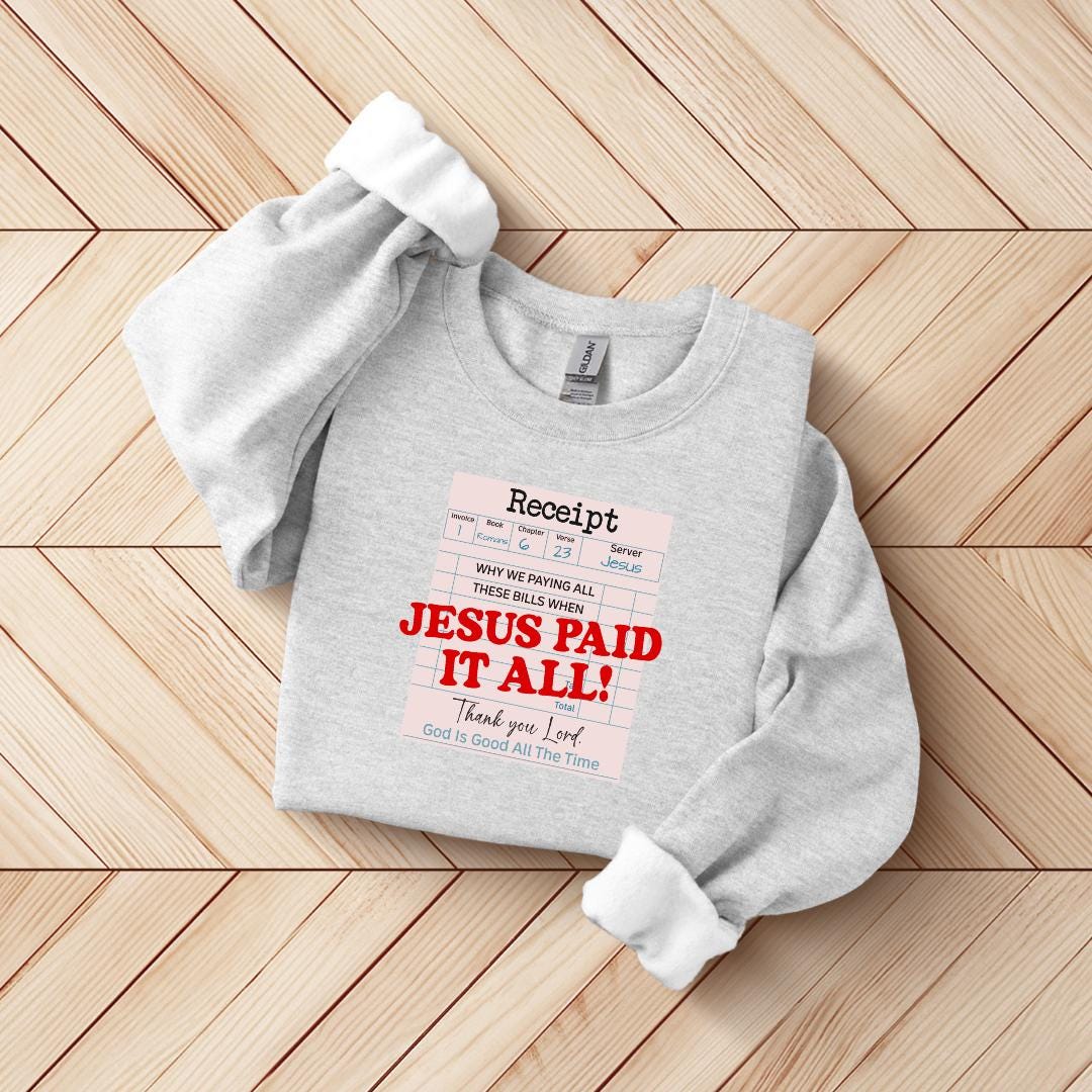 A gray sweatshirt with a printed message on it, laid out on a wooden surface.