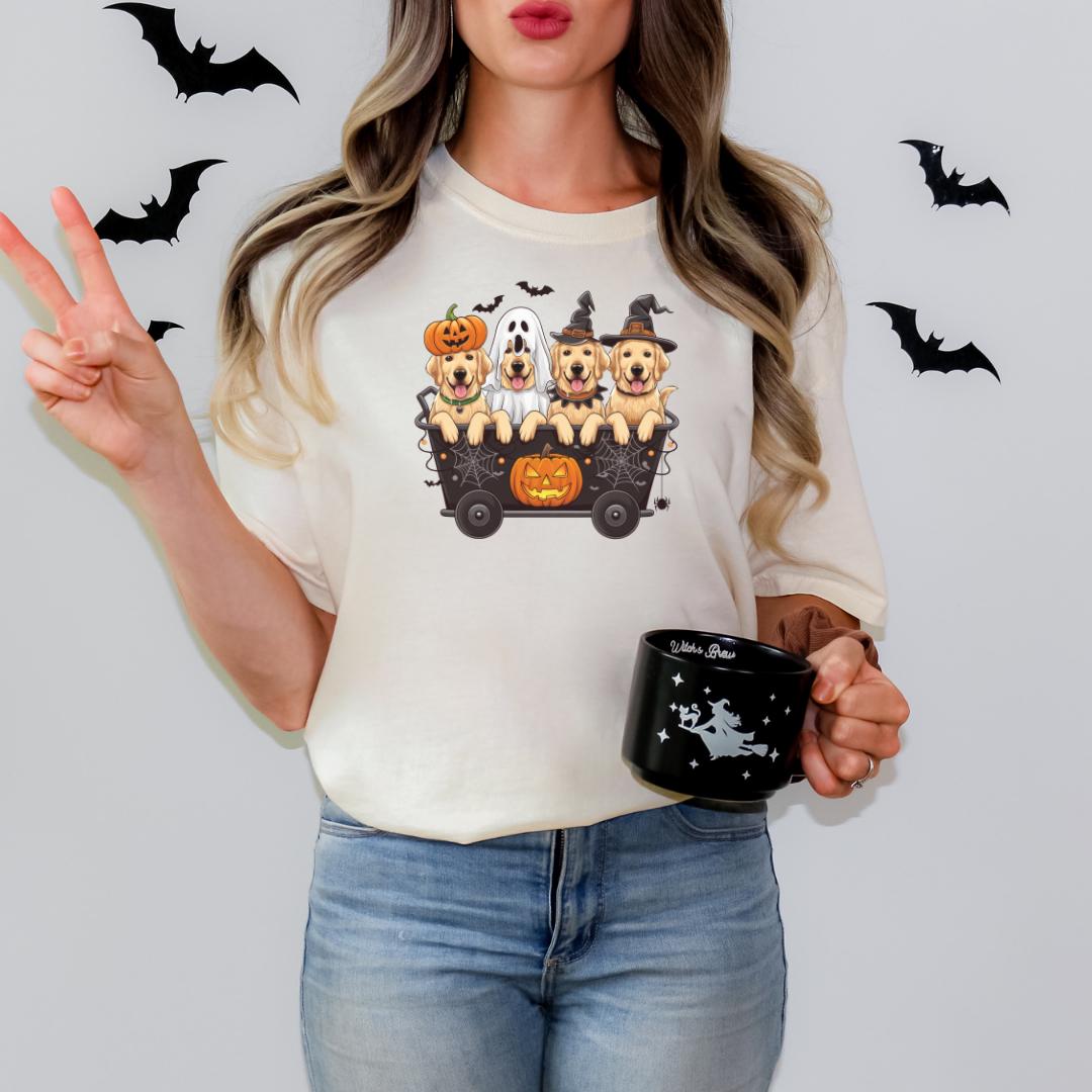 A woman is holding a mug with a Halloween-themed design featuring three dogs in a wagon, along with bats and a jack-o-lantern.