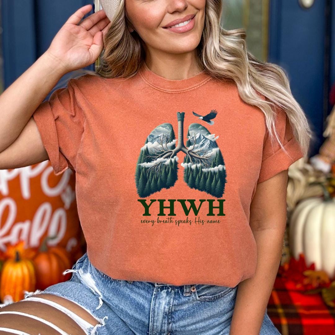 A woman wearing a t-shirt with a graphic design of lungs and a bird, along with the text "YHW every breath speaks its name".