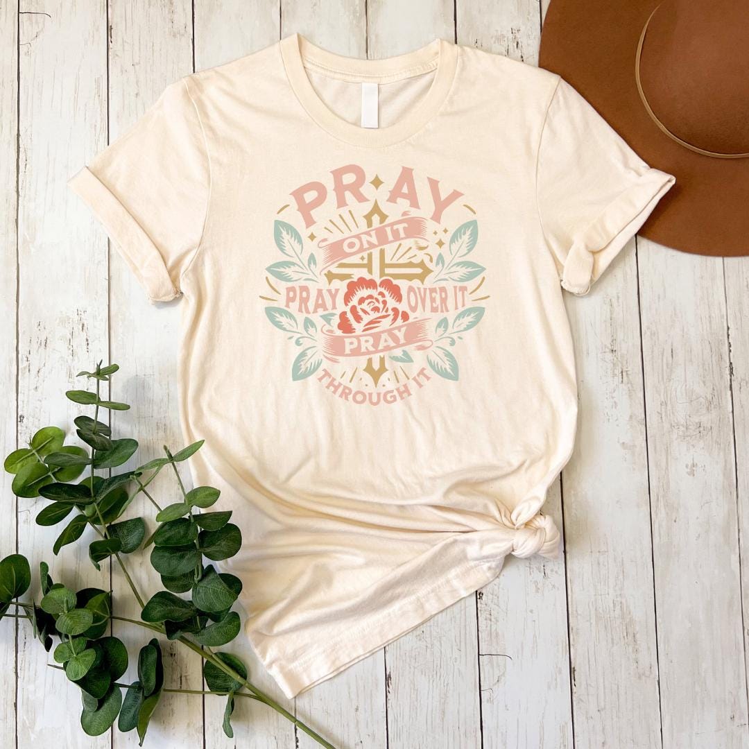 a t - shirt that says pray and a hat next to it