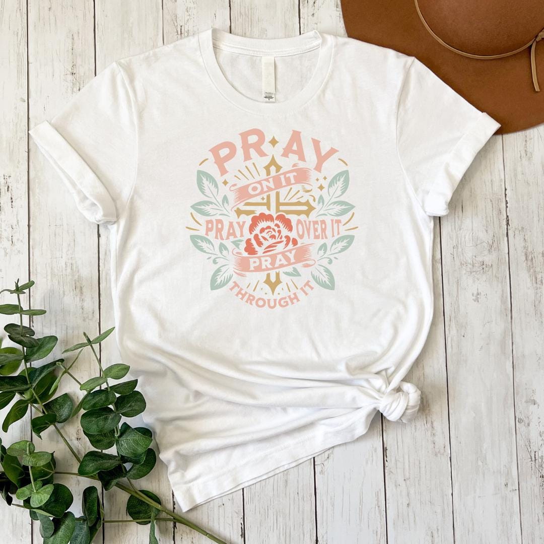a white t - shirt with the words pray and a rose on it