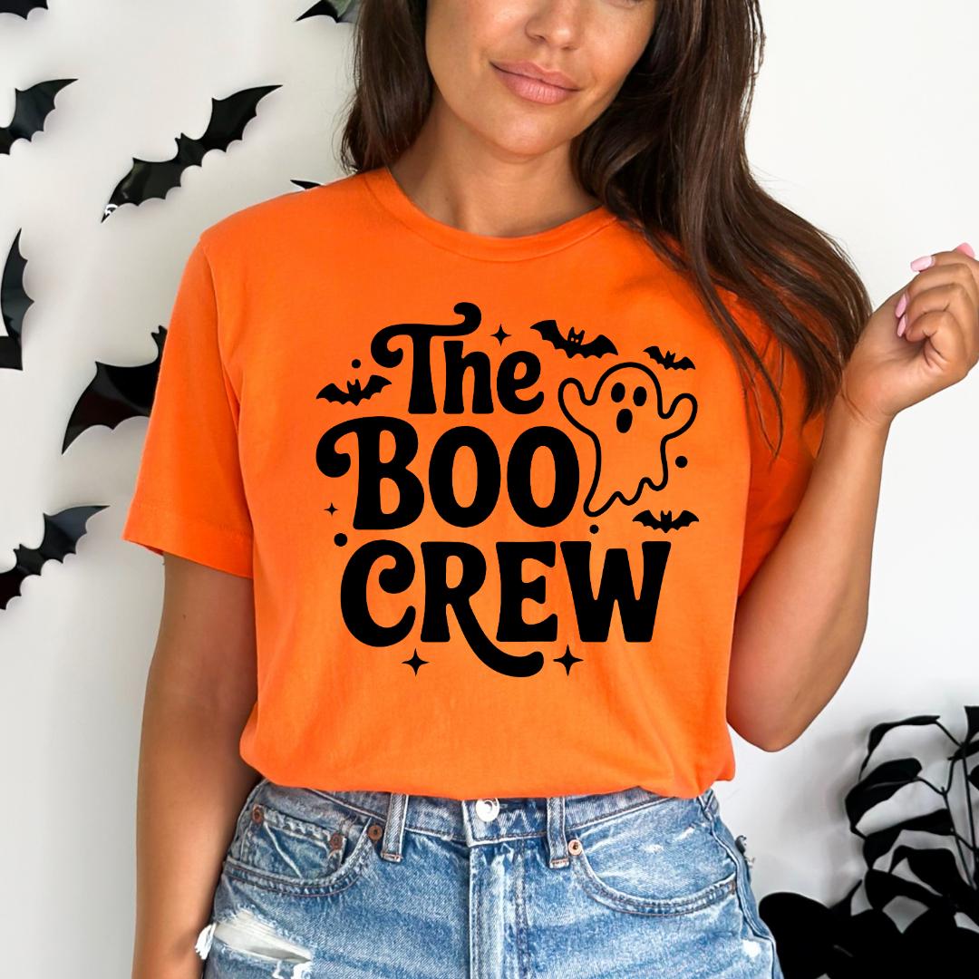 A woman wearing an orange t-shirt with the text "The Boo Crew" printed on it, along with a ghost and bats design.