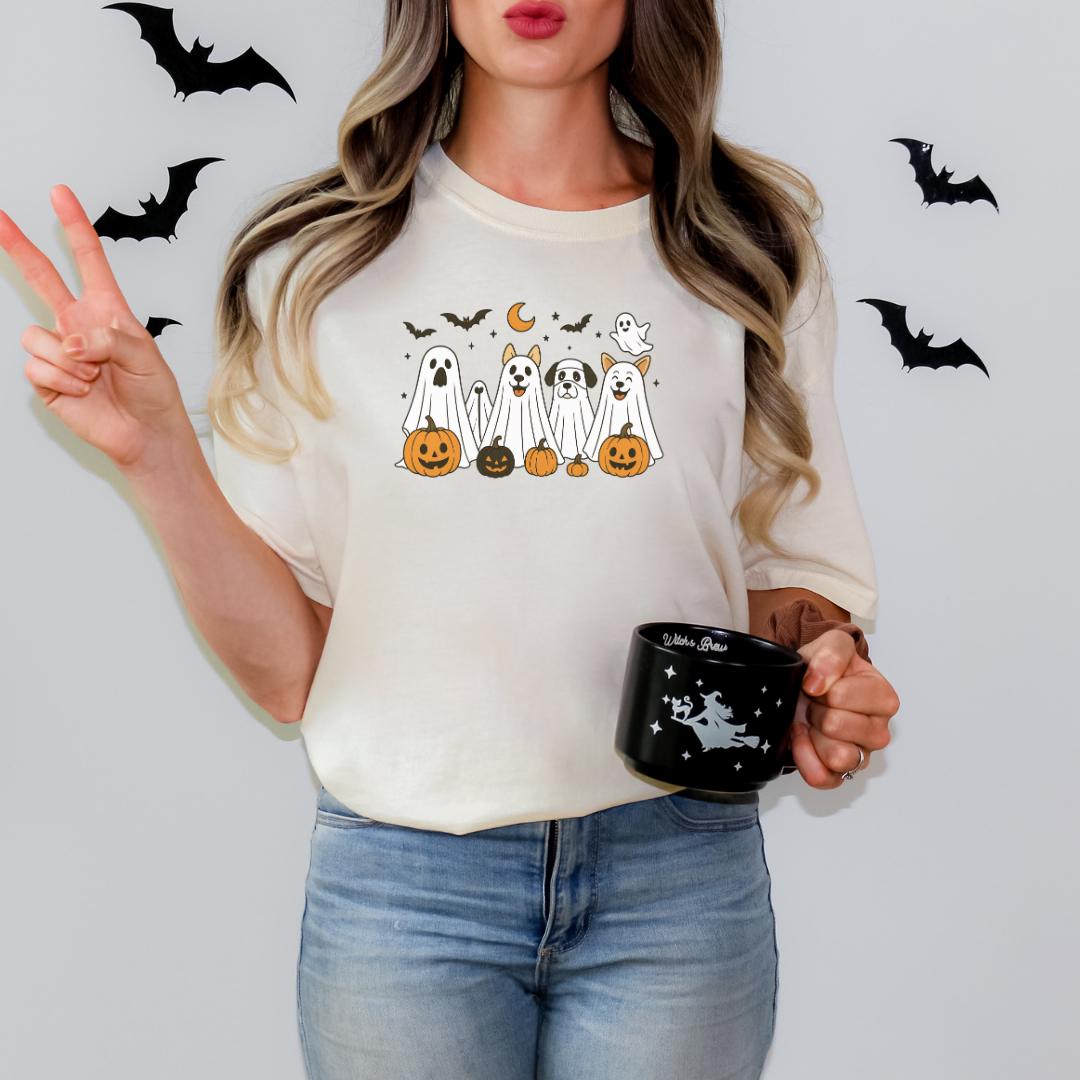 A woman wearing a white t-shirt with a Halloween-themed graphic and holding a black mug with a Halloween design.