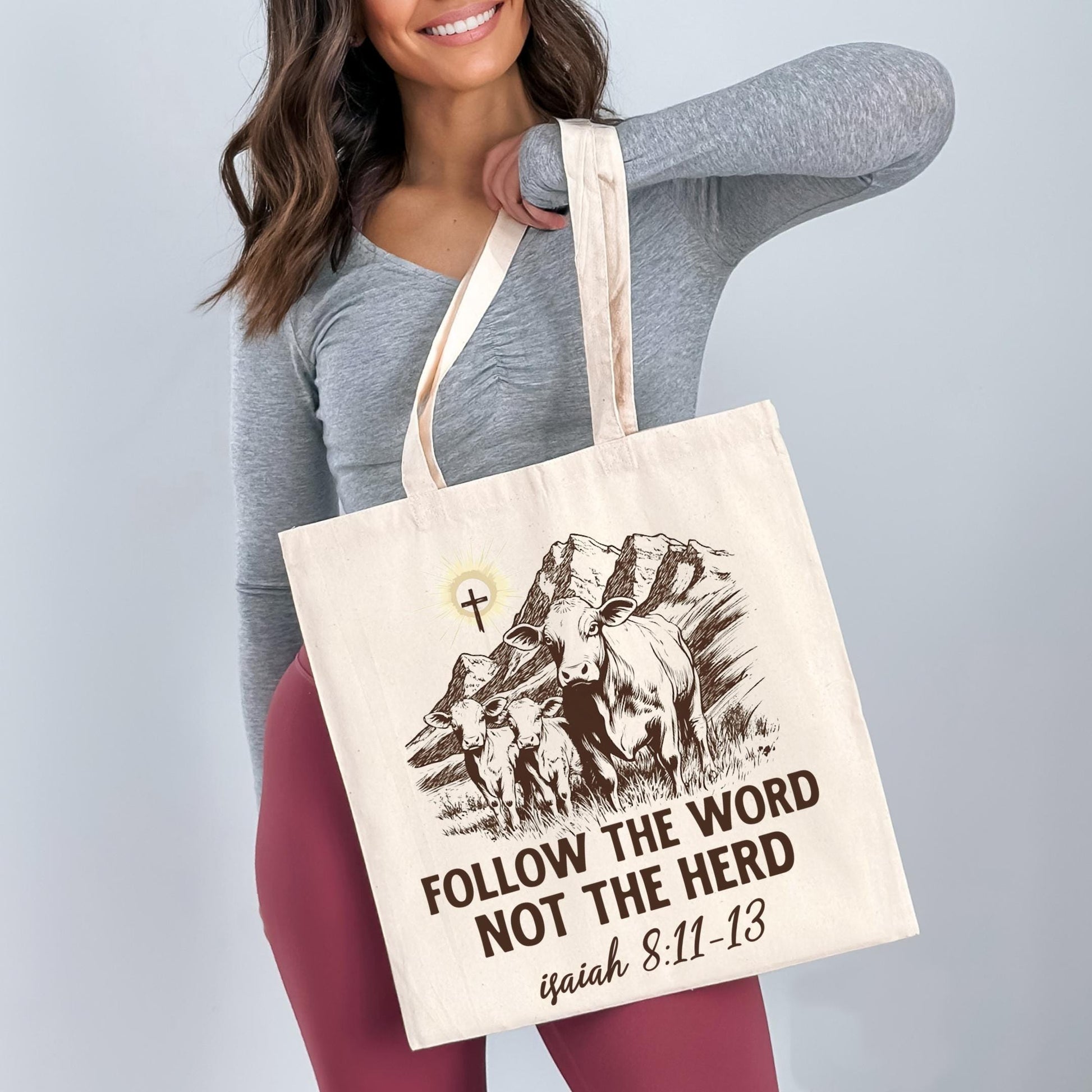 A woman is holding a large canvas tote bag with a printed design on it.
