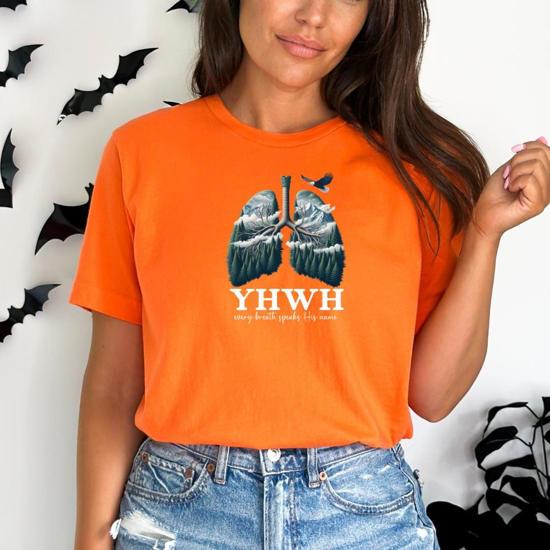 A woman wearing an orange t-shirt with a graphic design of lungs and the text "YHW" printed on it.