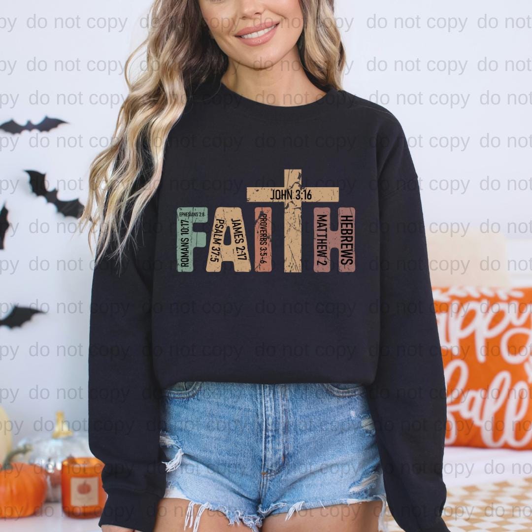 A woman wearing a black sweatshirt with a graphic design on it, standing in front of a Halloween-themed background.