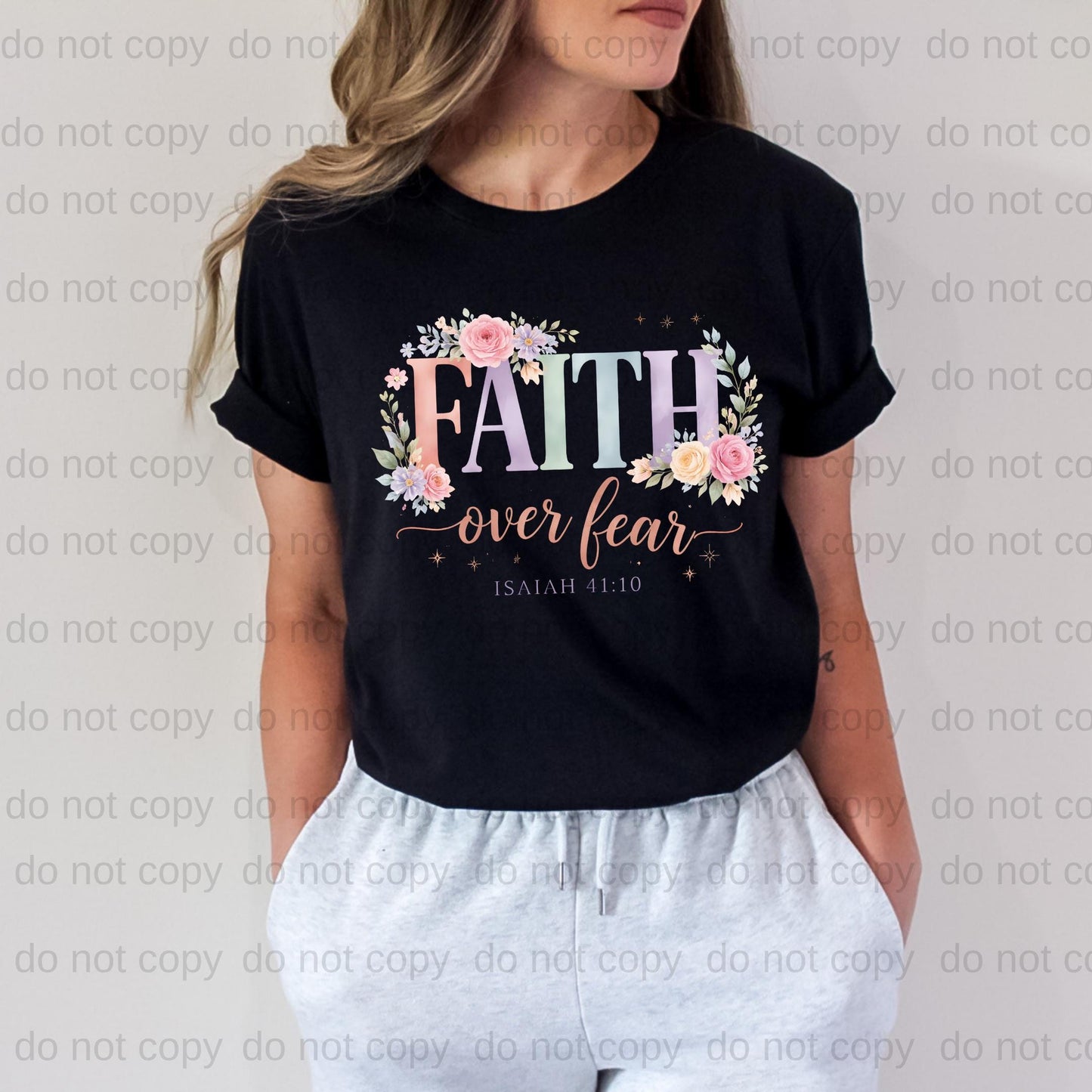 A woman wearing a black t-shirt with a floral design and the text "FAITH over fear" printed on it.