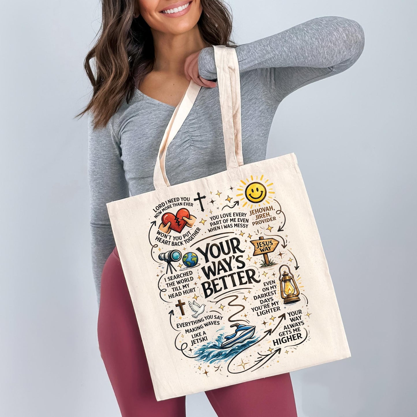 A woman holding a white tote bag with various illustrations and text on it.