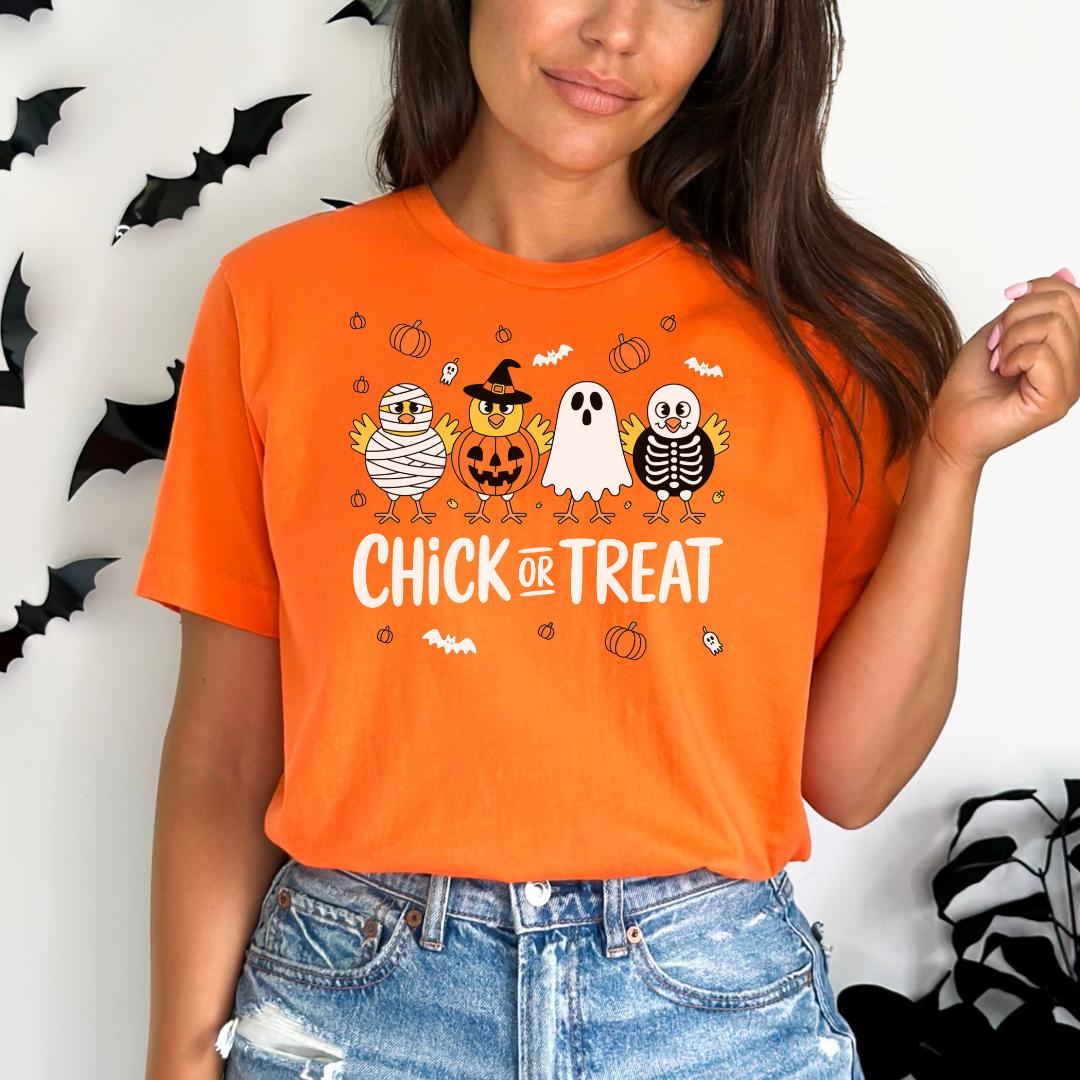 A woman wearing an orange t-shirt with a Halloween-themed graphic design, including a skeleton, ghost, and pumpkin.