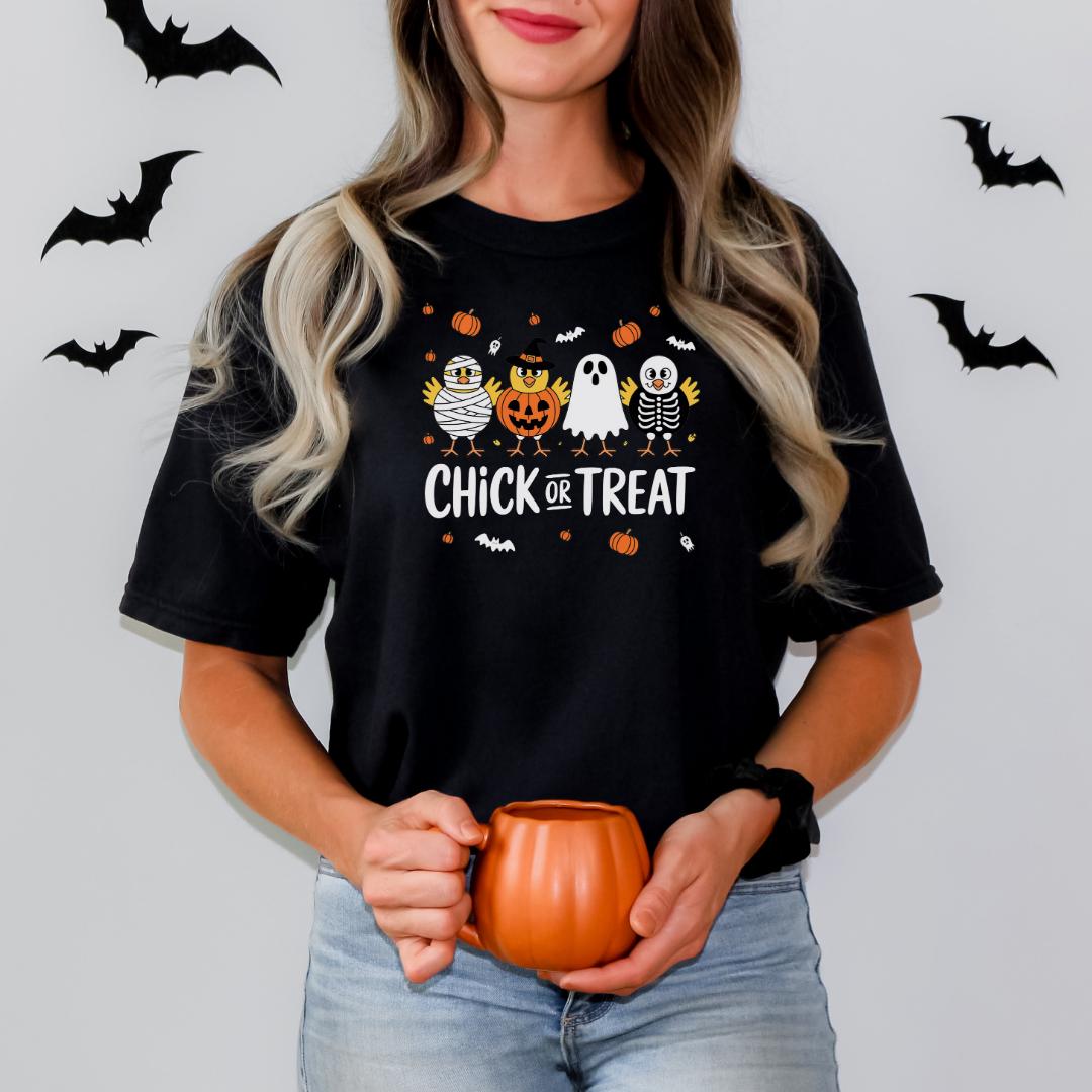 A woman wearing a black t-shirt with a Halloween-themed design and holding a pumpkin-shaped mug.