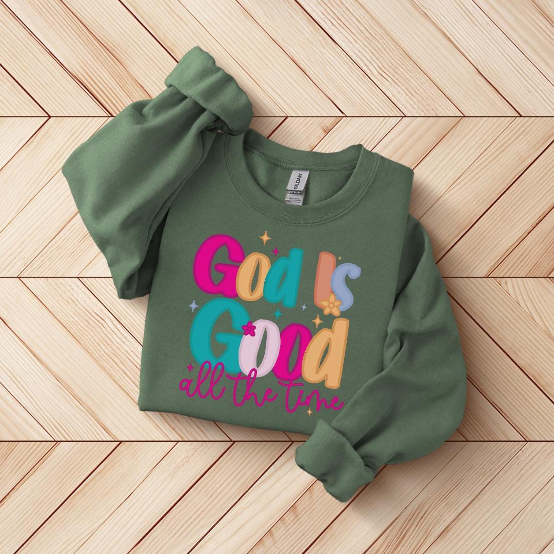 A green sweatshirt with colorful text and graphics printed on it, laid out on a wooden surface.