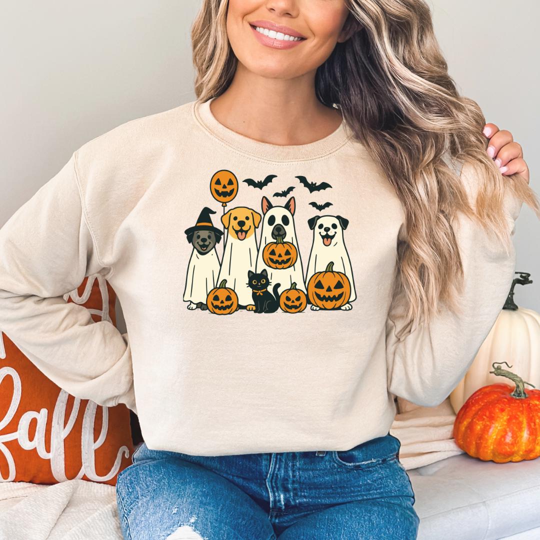 A woman wearing a white sweatshirt with a graphic of a group of dogs and Halloween pumpkins.