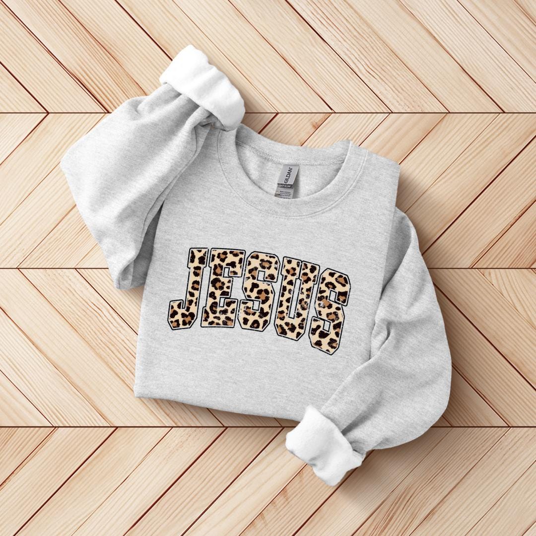 A grey sweatshirt with the word "JESUS" printed on it, featuring a leopard print design.