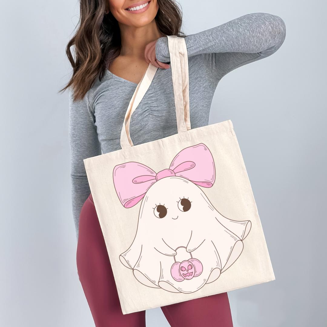 A woman is holding a large tote bag with a cartoon ghost design on it.