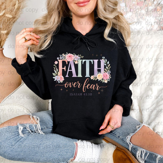A woman wearing a black hoodie with a floral design and the text "FAITH over fear" printed on it.