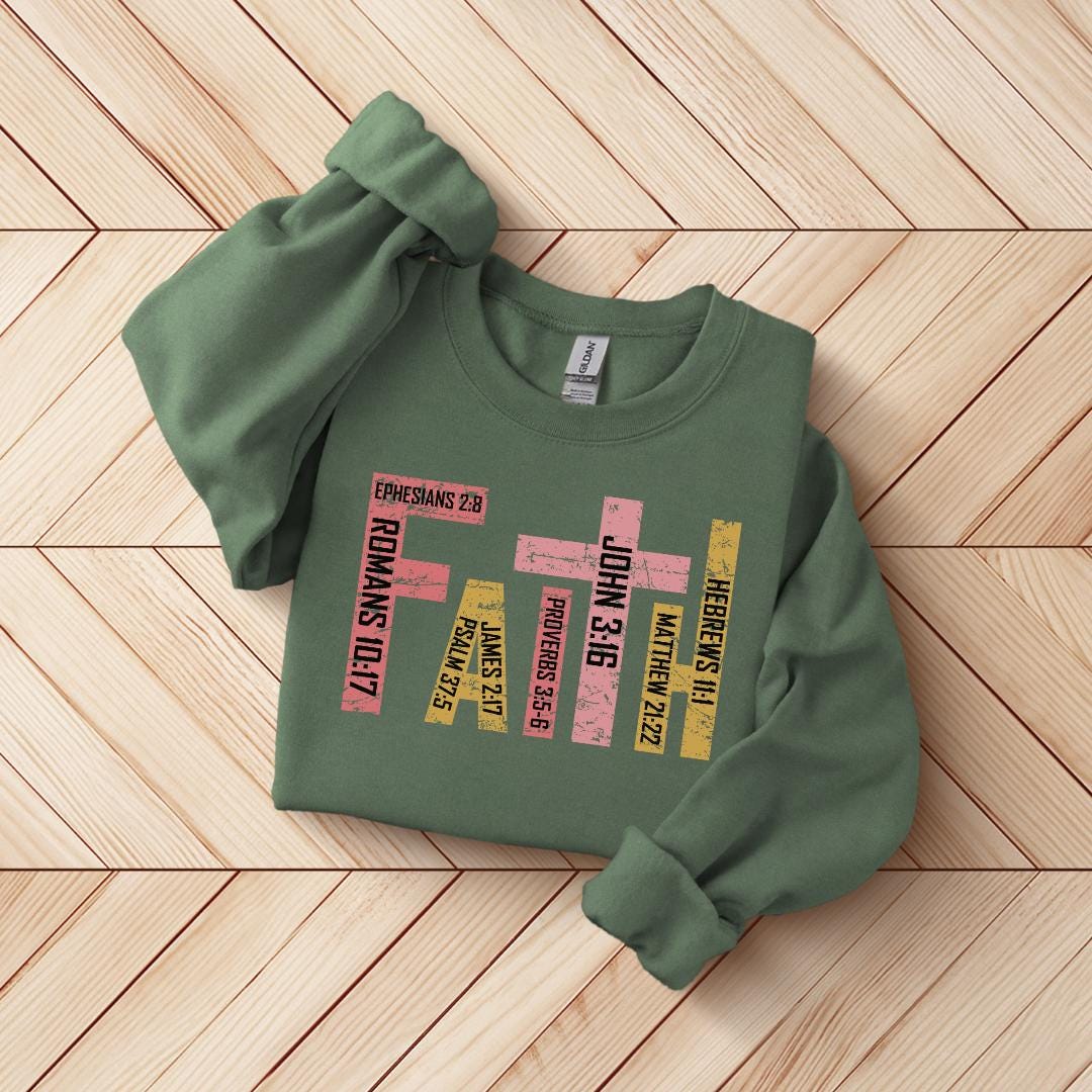 A green sweatshirt with a graphic design featuring text related to Christian beliefs, such as "Ephians 2B", "Faith", "John 3:16", "Hebrews 11:21", "Proverbs 3:16", "James 3:17", "2 Kings 17:25", "2 Chronicles 11:22", and "2 Chronicles 2:22".