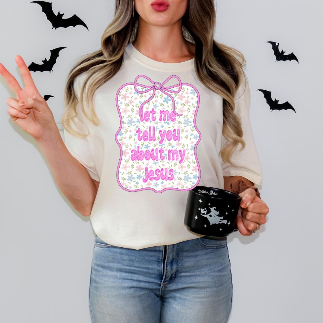 A woman wearing a white t-shirt with a graphic design and holding a black mug with a star and bat design.