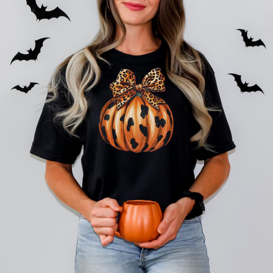 A woman with long blonde hair is holding a pumpkin-shaped mug in front of her.