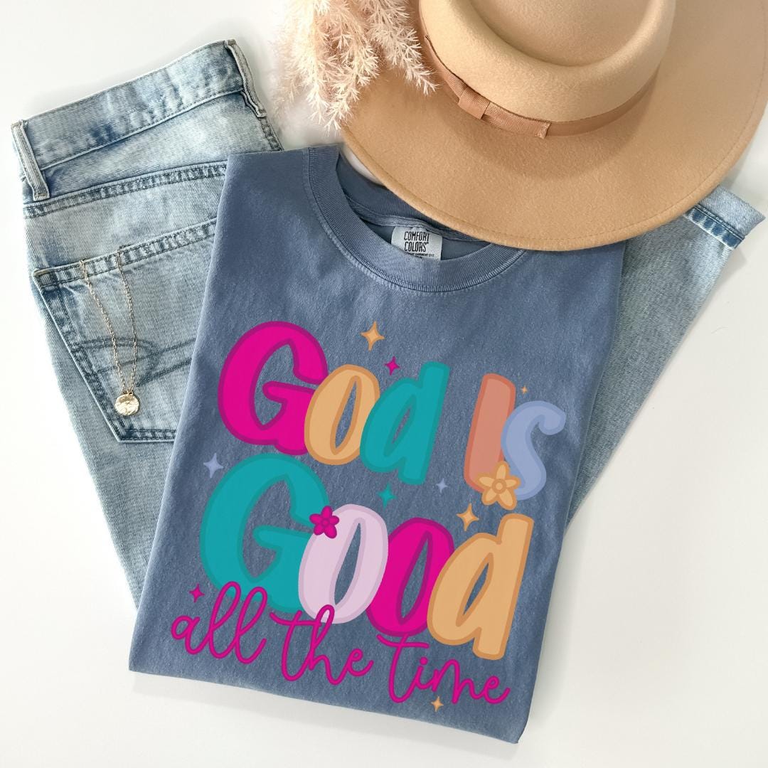 A casual outfit consisting of a blue t-shirt with a colorful graphic, a pair of jeans, and a beige hat.
