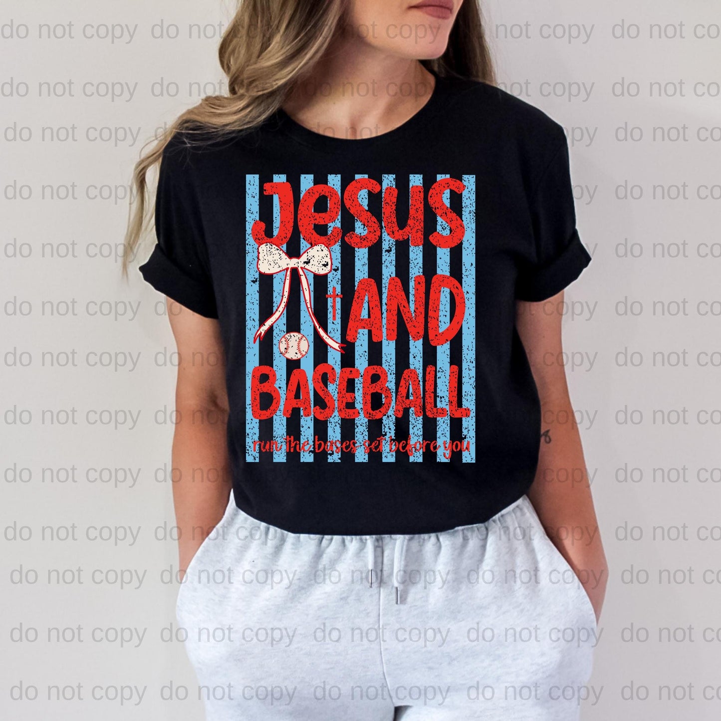 A woman wearing a black t-shirt with a graphic design featuring the text "JESUS AND BASEBALL" and a baseball graphic.