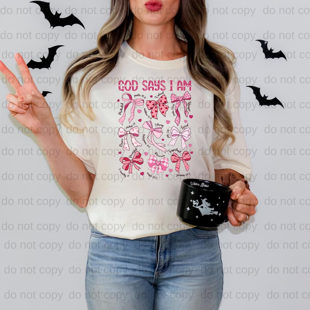 A woman is standing in front of a wall with bats, wearing a white t-shirt with a graphic design and holding a black mug.