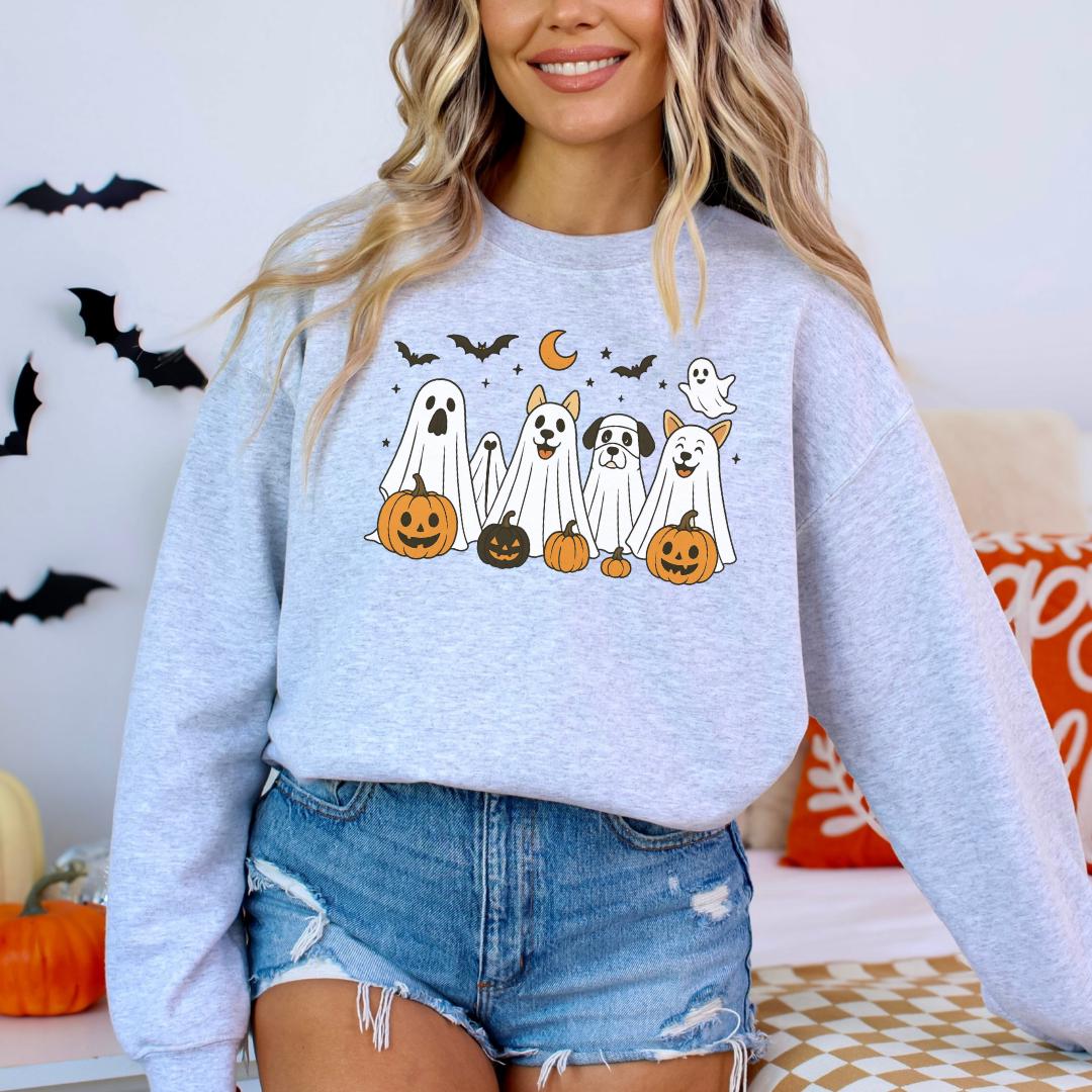 A woman wearing a grey sweatshirt with a Halloween-themed graphic of ghostly figures and jack-o-lanterns.