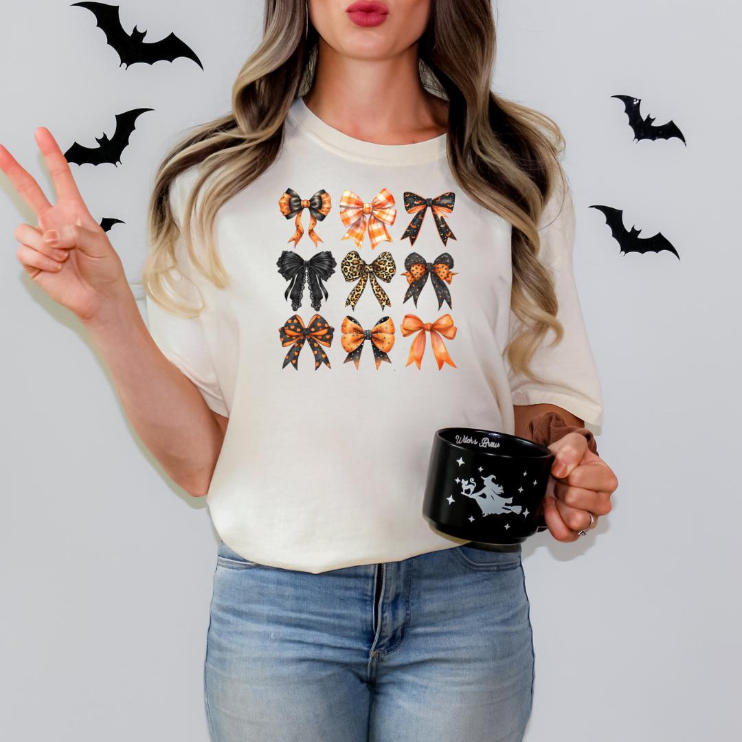 A woman is standing against a white background, wearing a white t-shirt with a graphic of bows and holding a black mug with a white design.