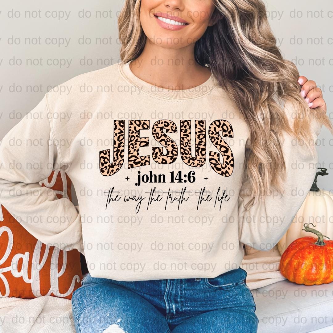 A woman wearing a white sweatshirt with a leopard print design and text printed on it, smiling and posing for the camera.