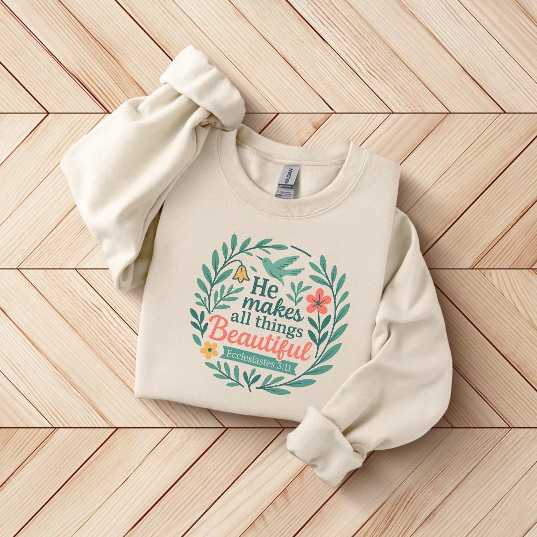 A beige sweater with a printed design on it, featuring a quote from the Bible verse Ecclesiastes 3:11.