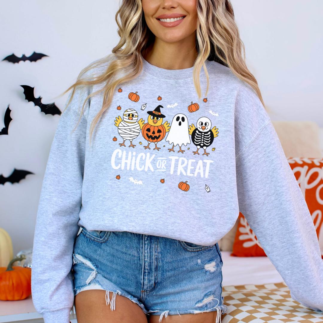 A woman wearing a grey sweatshirt with a Halloween-themed graphic design featuring cartoon birds and a pumpkin.