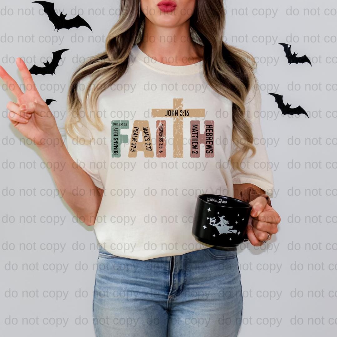 A woman is standing against a wall with bats flying around her. She is wearing a white t-shirt with a graphic design and holding a black mug with a star and a bat printed on it.