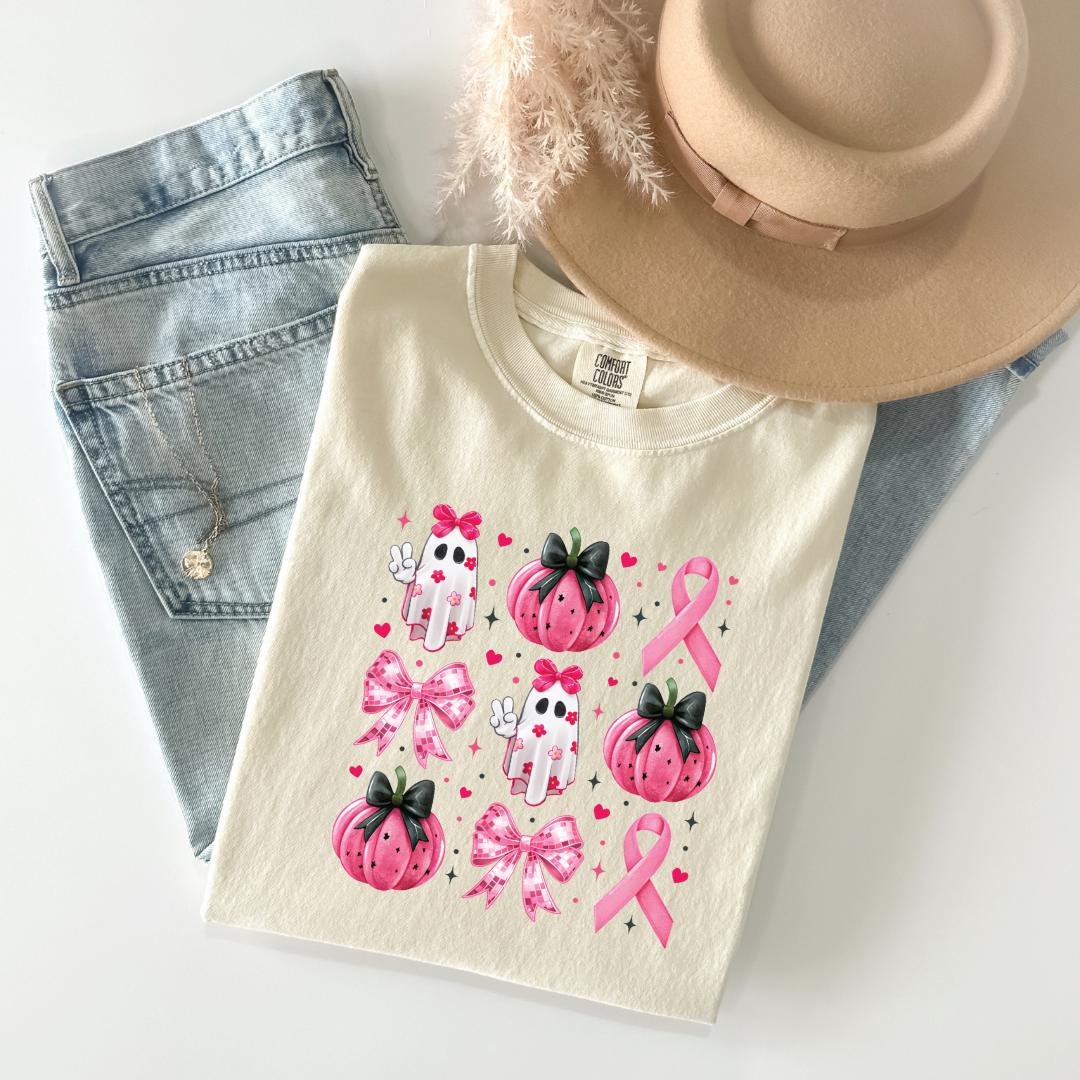 a casual outfit consisting of a white t-shirt with a graphic design featuring pink pumpkins, bows, and a pink ribbon, along with a pair of jeans and a beige hat.