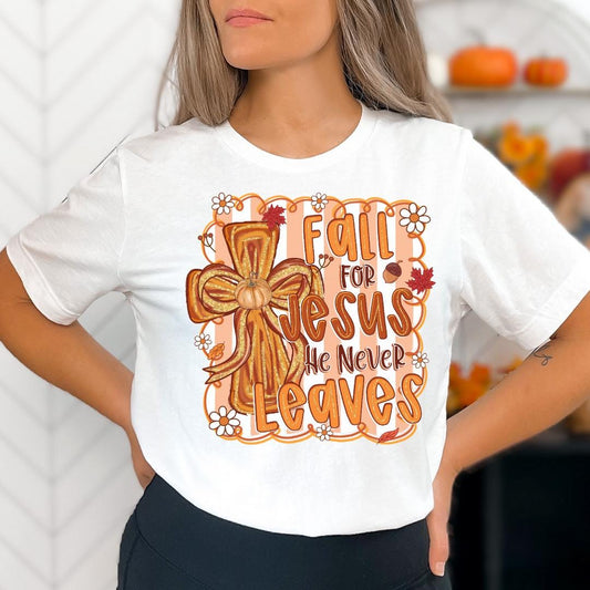 A woman wearing a white t-shirt with a graphic design featuring a cross and the text "Fall for Jesus, he never leaves" printed on it.